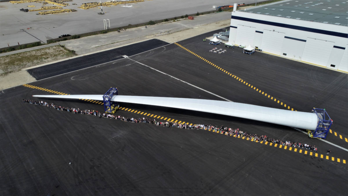 LM Wind Power employees next to a wind turbine blade